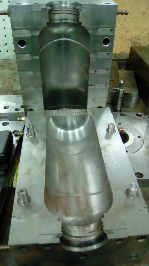 Open plastic-bottle blow mould showing two bottle-shaped cavity halves, threaded neck regions and locating pins.